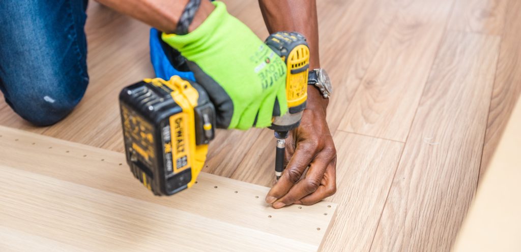 When to Call in the Professionals for Home Repair | Powell Realtors (showing a man with drill and lumber)