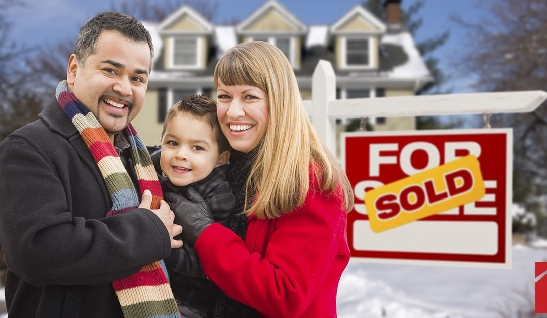 Family standing in front of a house with a "sold" sign in the winter | Powell Realtors